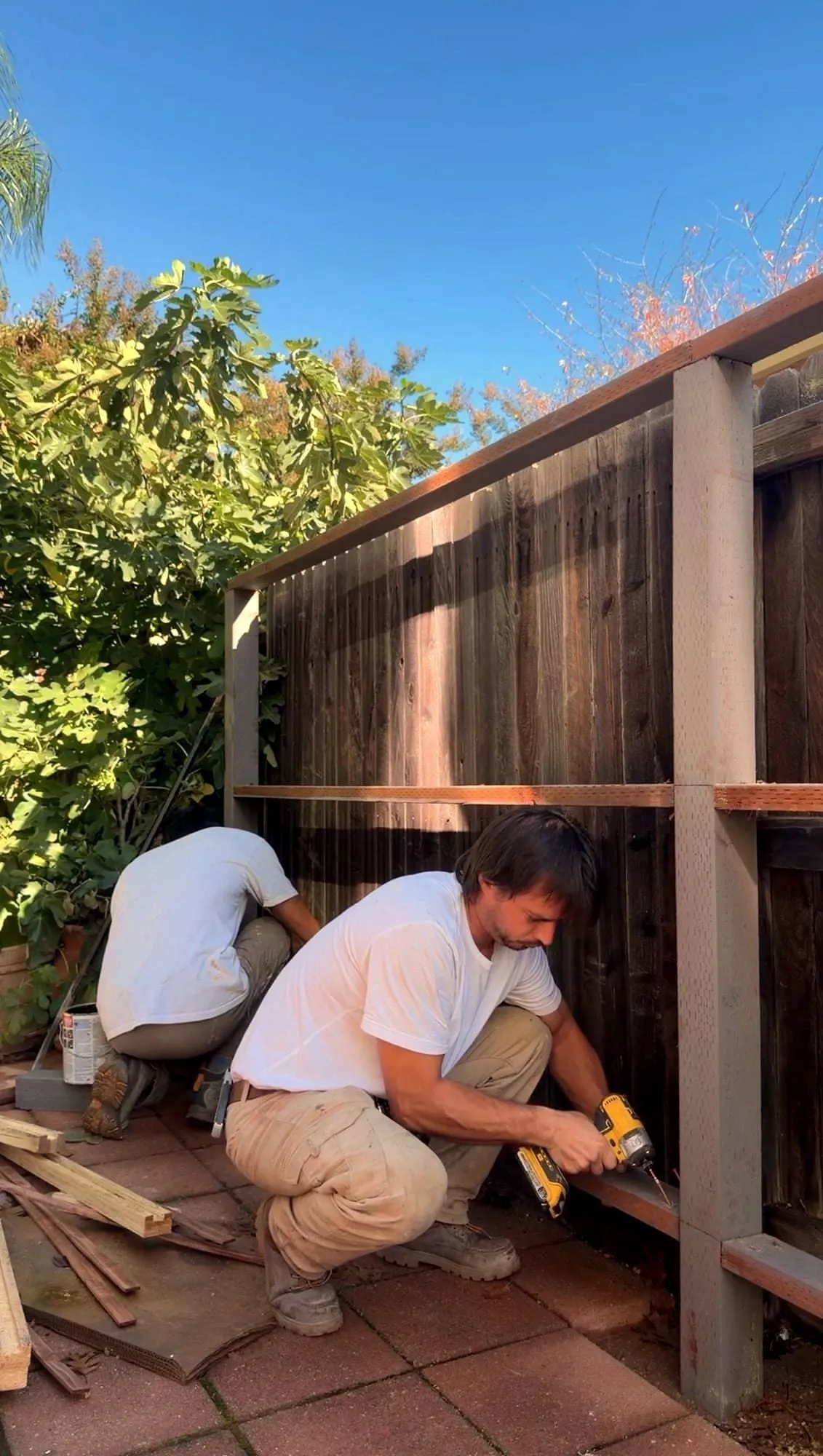 Serj and a second man screwing rails onto new fence posts in a Sacramento-area backyard
