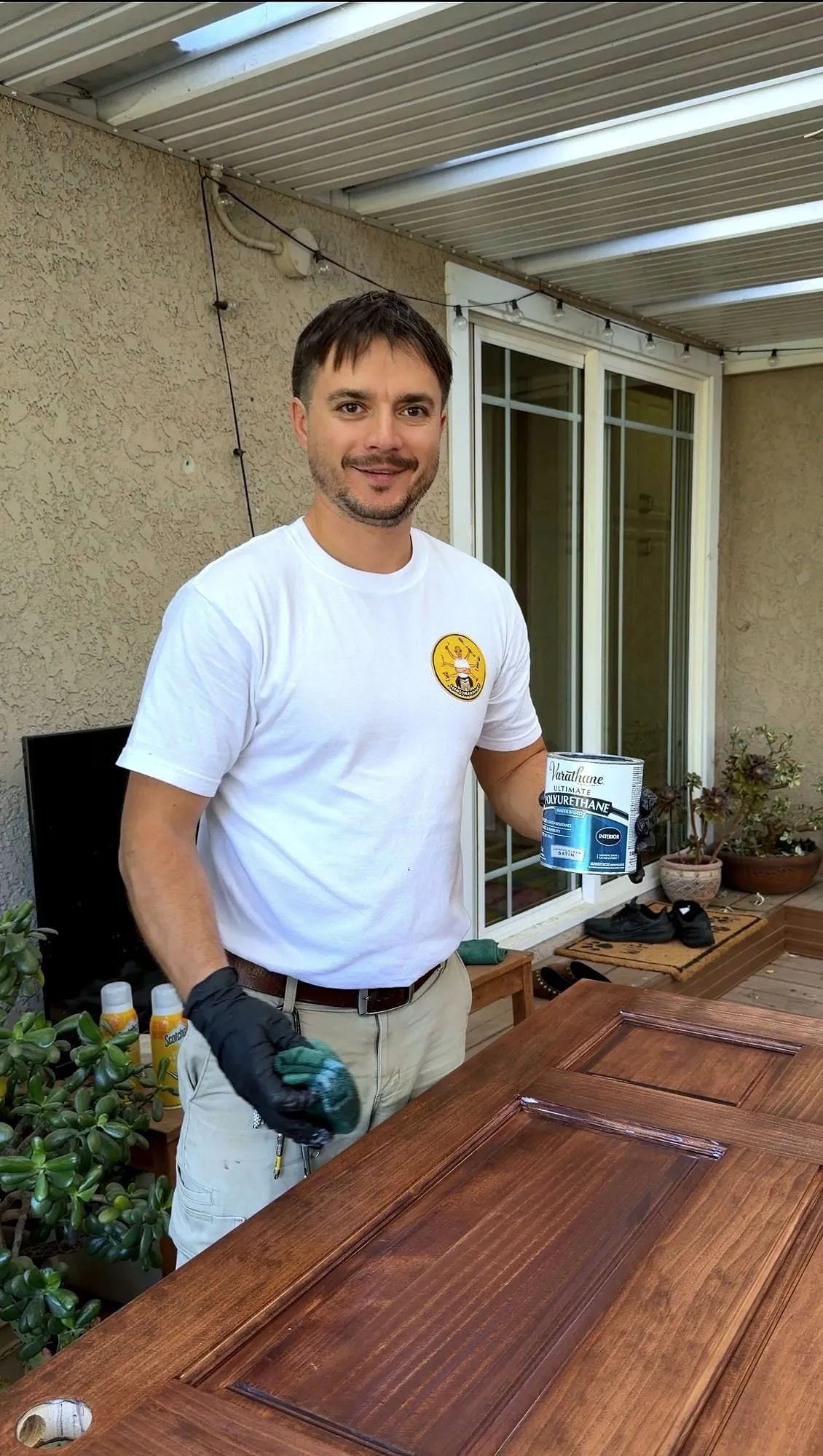Serj refinishing a door, in his branded shirt, on a Sacramento job