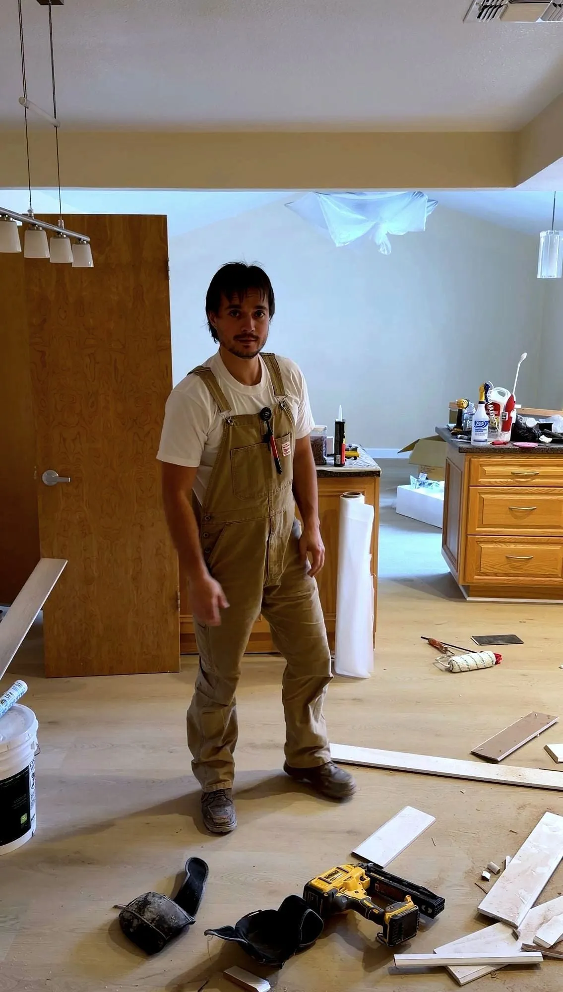 Planks going down over new underlay, nailer on the floor beside him.