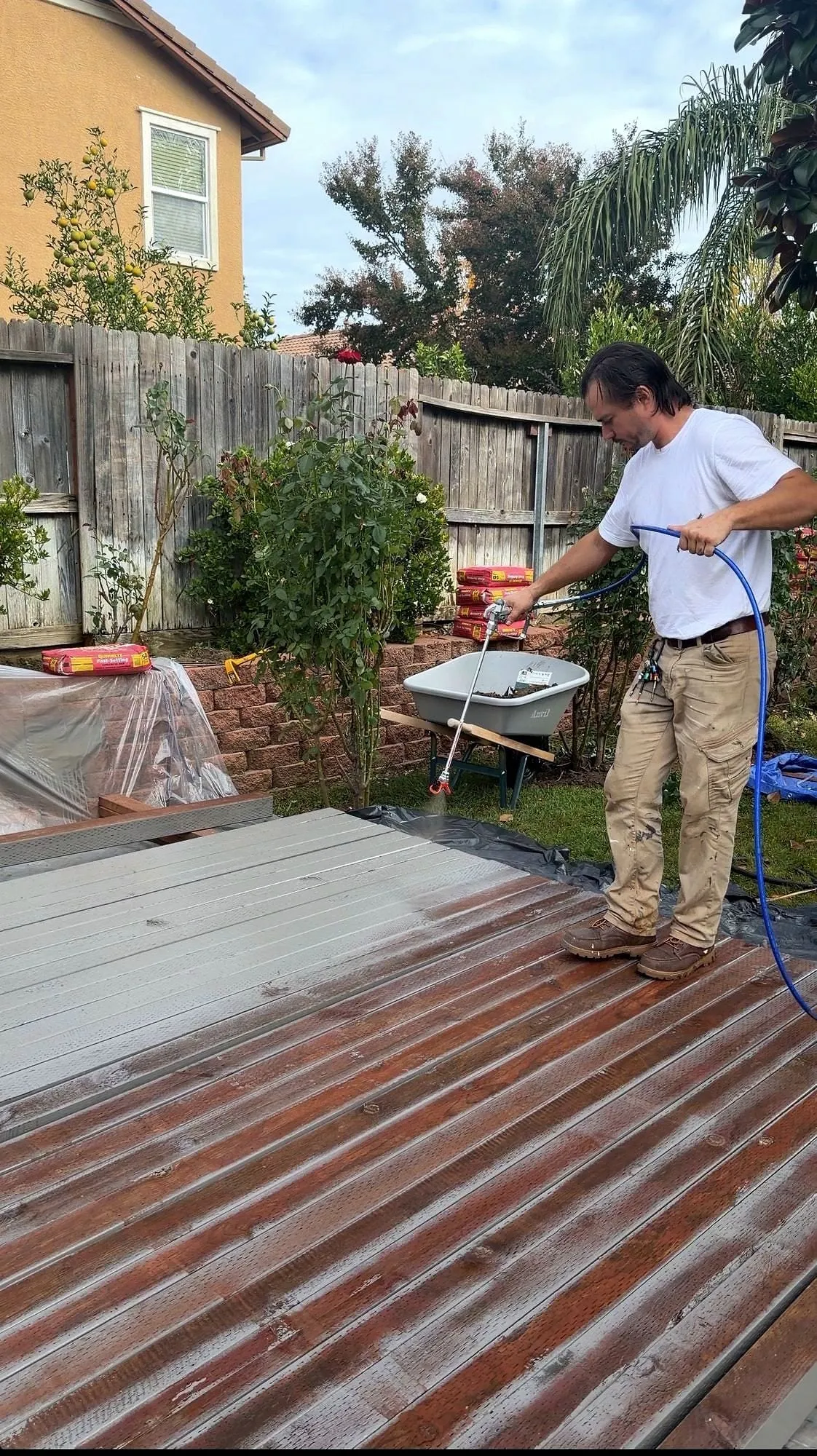 Corrugated roofing and framing stacked across a patio during a deck teardown