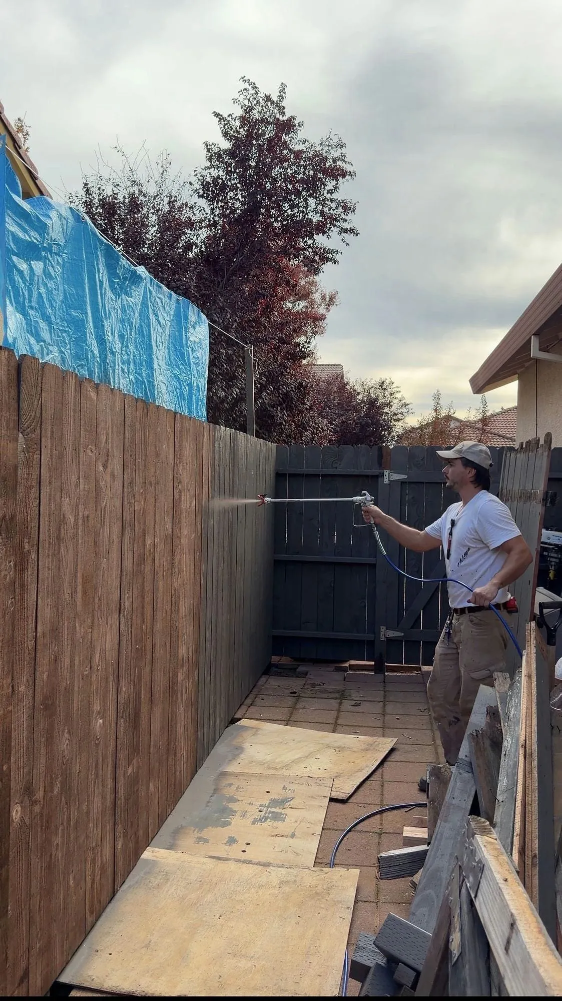 Spraying stain onto a newly built timber fence with a pump sprayer