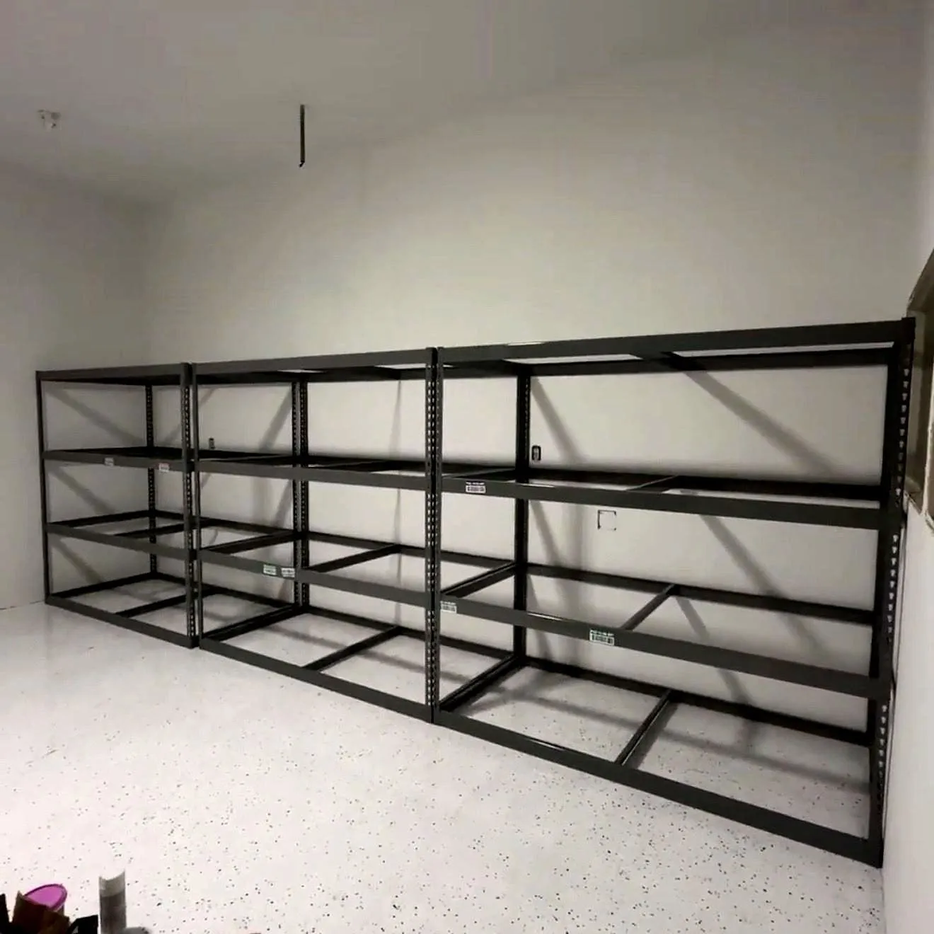 Garage racking, three bays, level across a floor that slopes to the door.